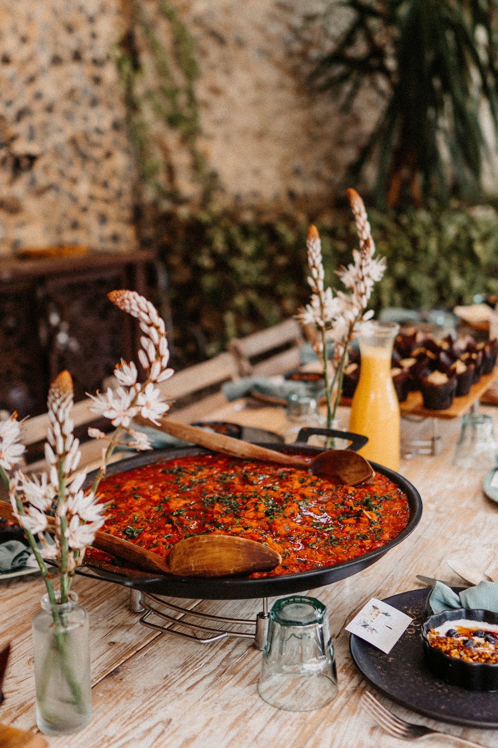 Gedeckter Tisch mit Paella und Blumen