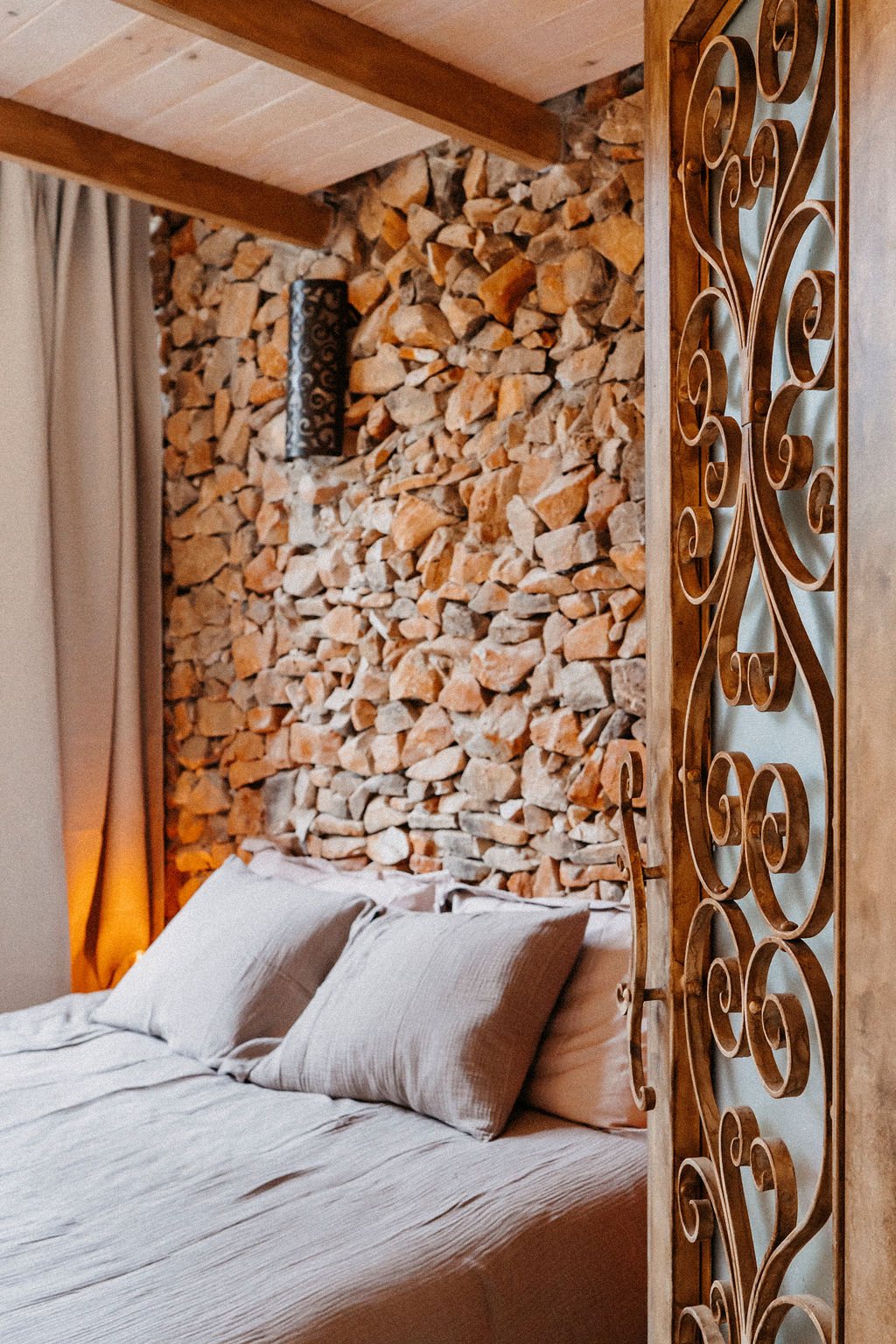 Zimmer mit Natursteinwand und hellem Bett