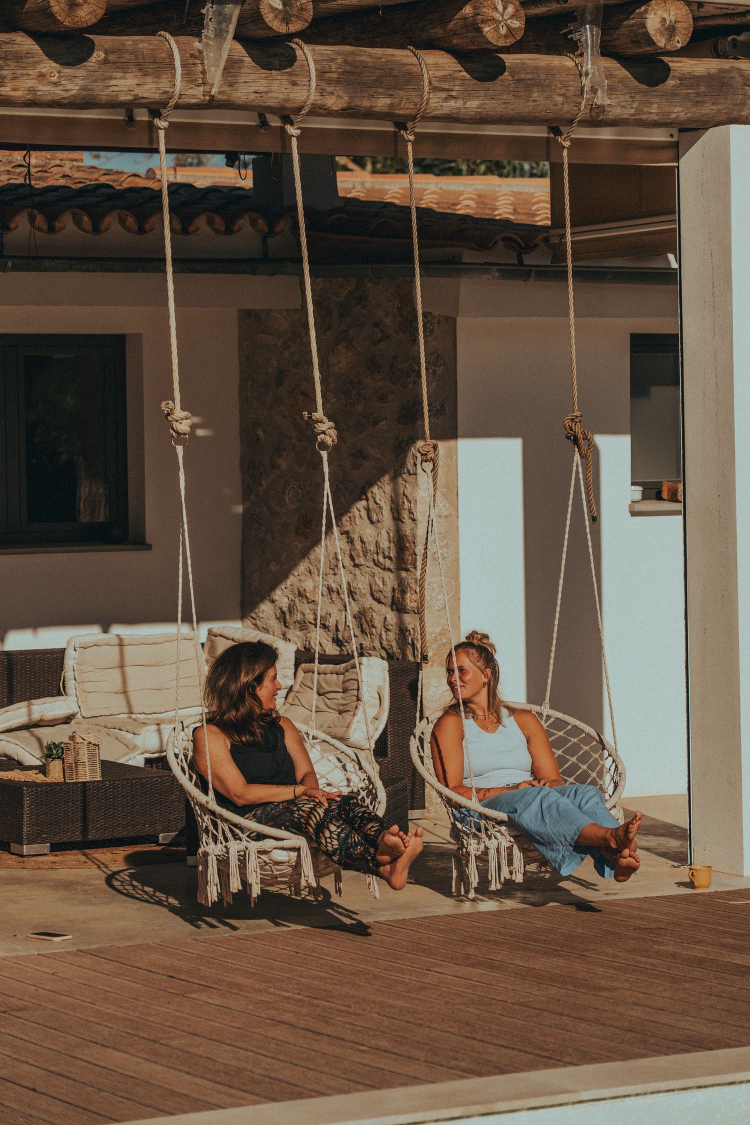 Zwei Teilnehmerinnen entspannen in Hängesesseln auf der Terrasse