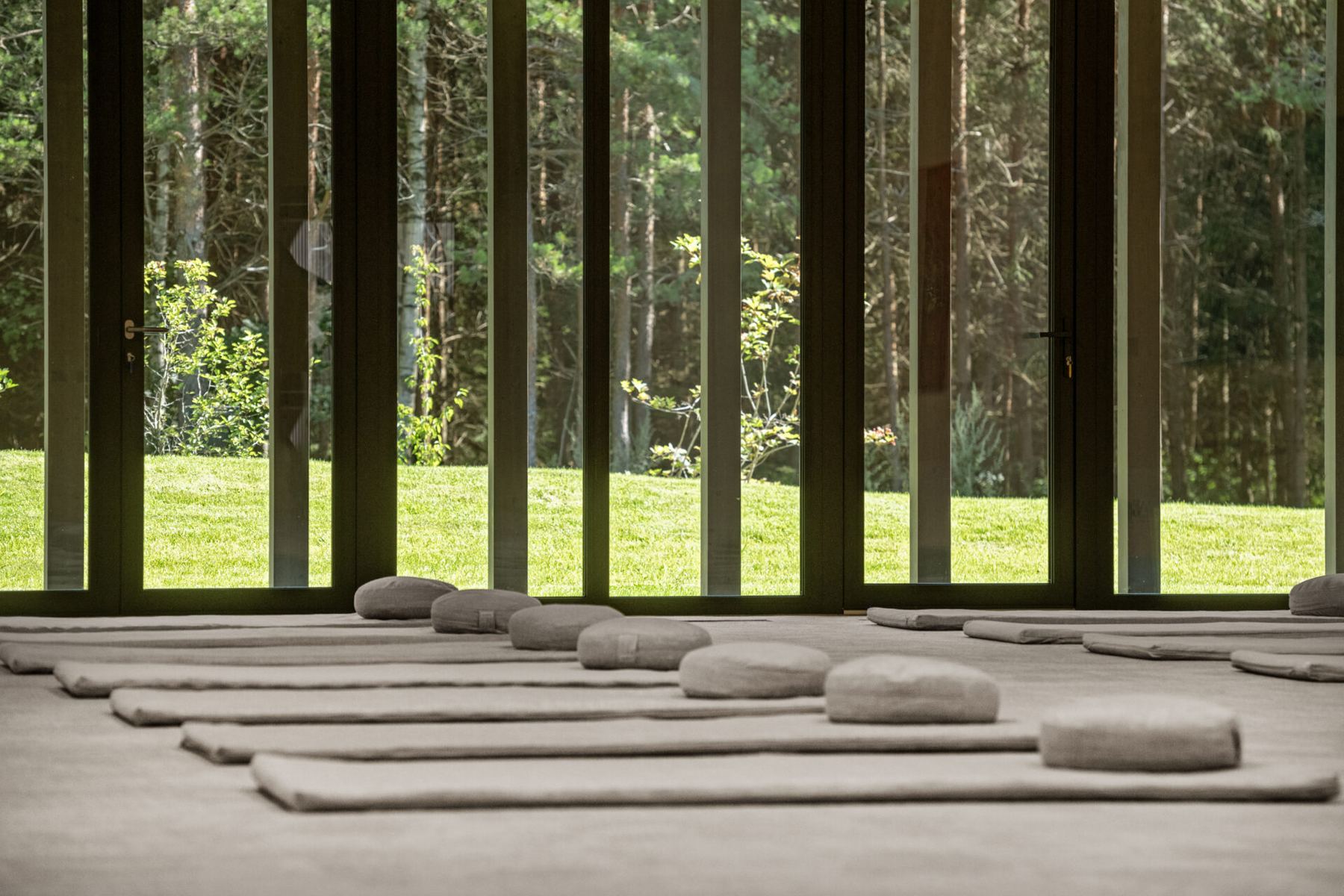Der Forest Palace: Matten und Kissen in Reihen vor der Fensterfront zum Wald