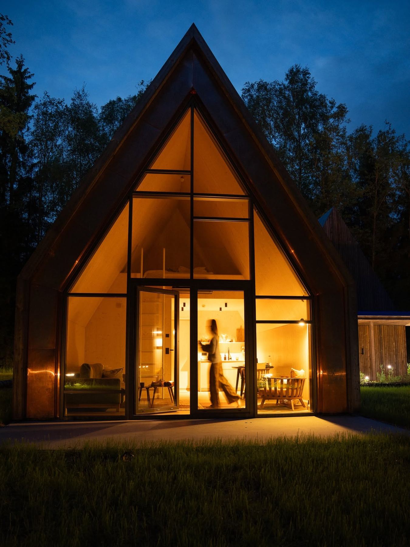 Ein Waldloft bei Nacht, das Giebelfenster leuchtet warm
